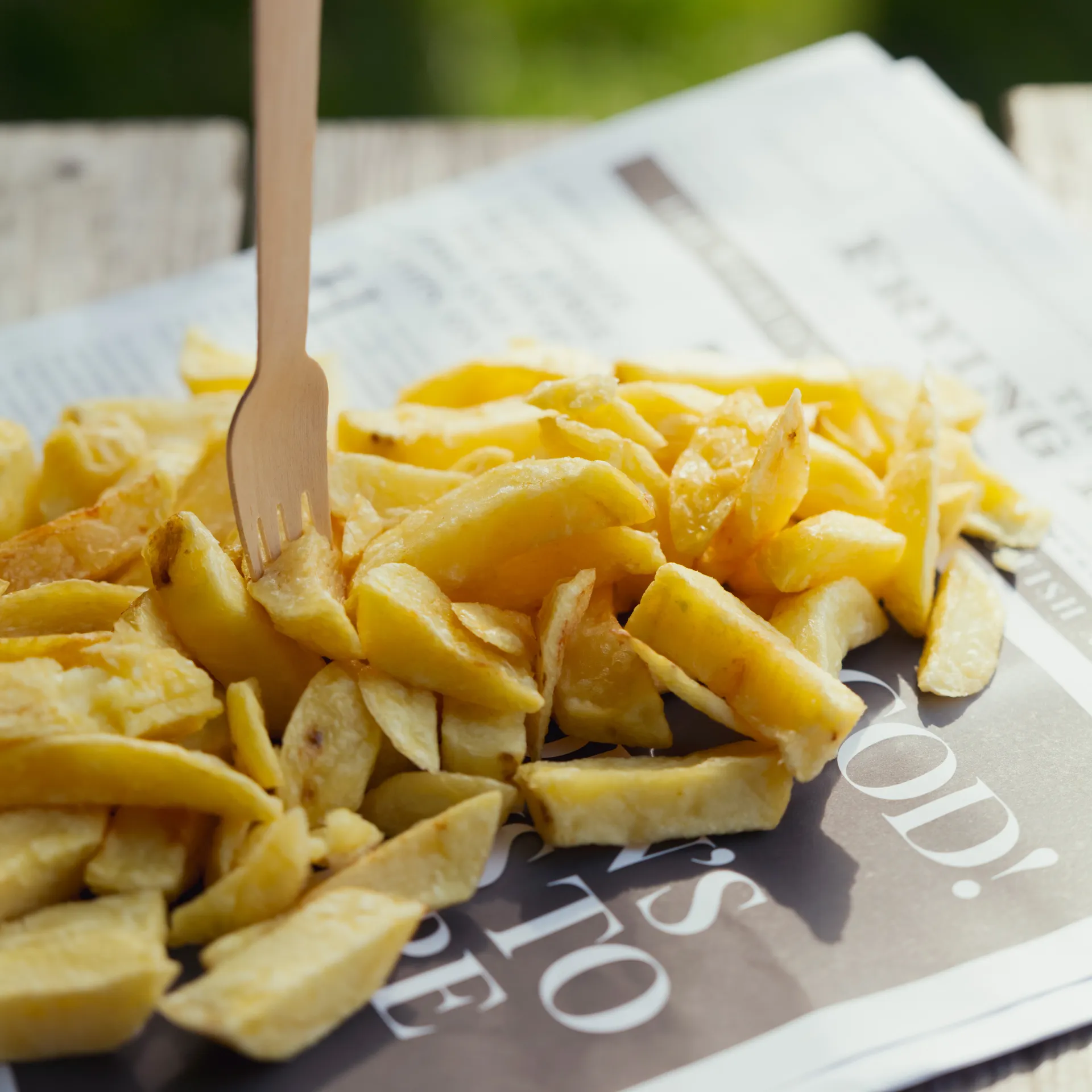 Chips with a wooden fork on a newspaper